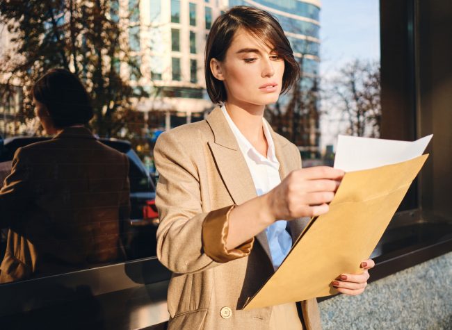 Young attractive stylish businesswoman confidently working with papers on street